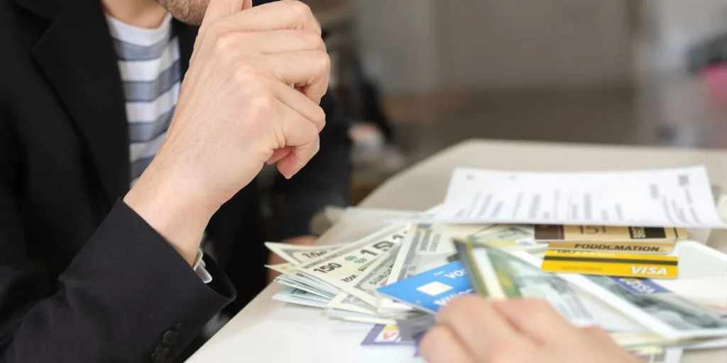 Persona examinando billetes y tarjetas bancarias.